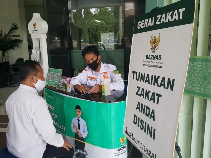 Petugas Badan Amil Zakat Nasional (BAZNAS) Kota Tangerang tengah melayani salah satu warga di Kota Tangerang yang ingin membayar zakat fitrah.