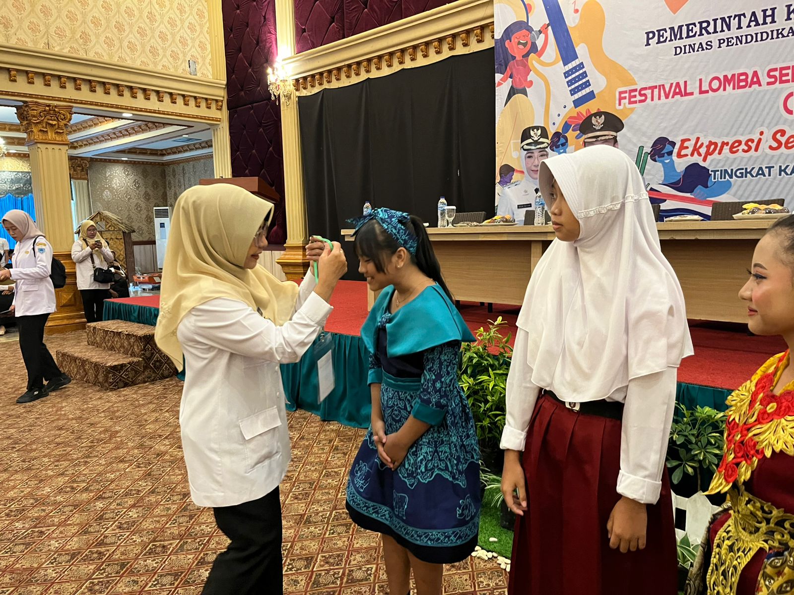 Bupati Pandeglang Raden Dewi Setiani secara simbolis menyempatkan kartu peserta lomba FLS3N kepada salah seorang siswa, saat acara pembukaan di aula salah satu hotel di Pandeglang, Rabu (14/5).