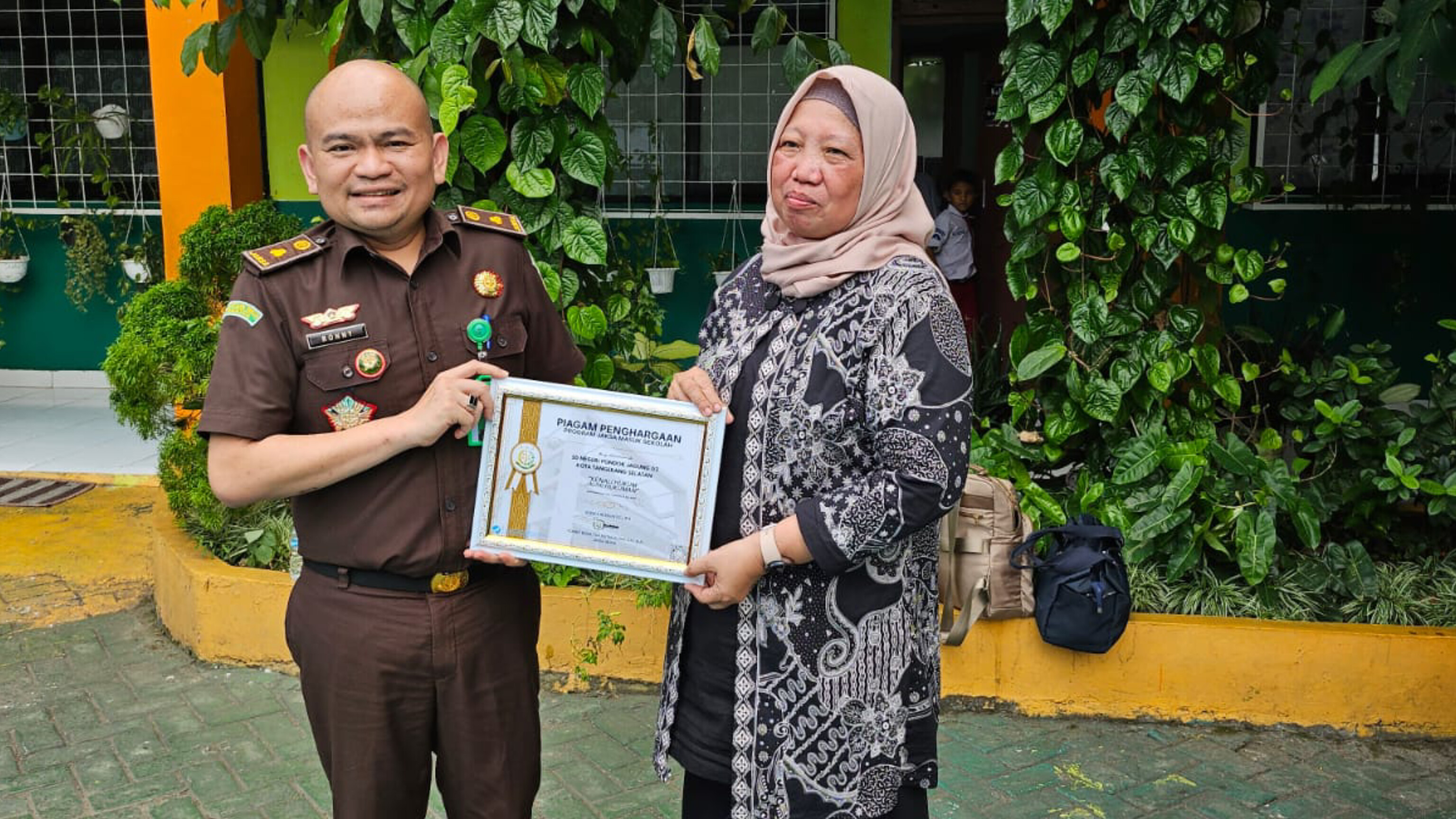 Jaksa Masuk Sekolah di SDN Pondok Jagung 02 Kepala Seksi Intelijen Kejaksaan Negeri Kota Tangerang Selatan, Tonny, menyerahkan piagam penghargaan kepada Kepala SDN Pondok Jagung 02, Sawiah, sebagai bentuk apresiasi dalam kegiatan “Jaksa Masuk Sekolah” di Tangerang Selatan, Kamis (31/7/2025). (Ist)