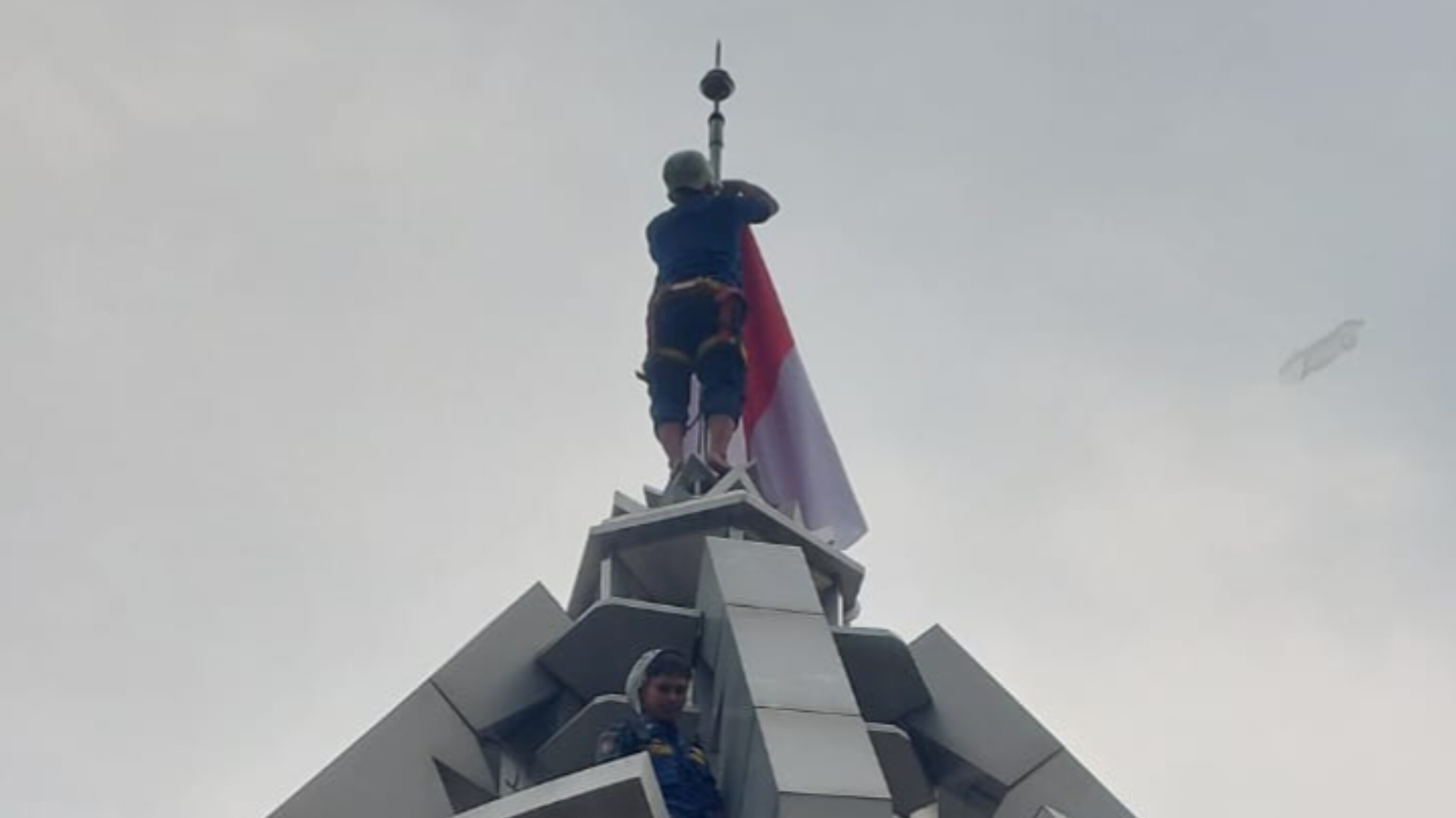 Damkar Tangsel mengibarkan Sang Saka Merah Putih di puncak tugu yang menjulang tinggi, tanpa akses tangga, dan dengan alat terbatas, Kamis (14/8). (Ist)