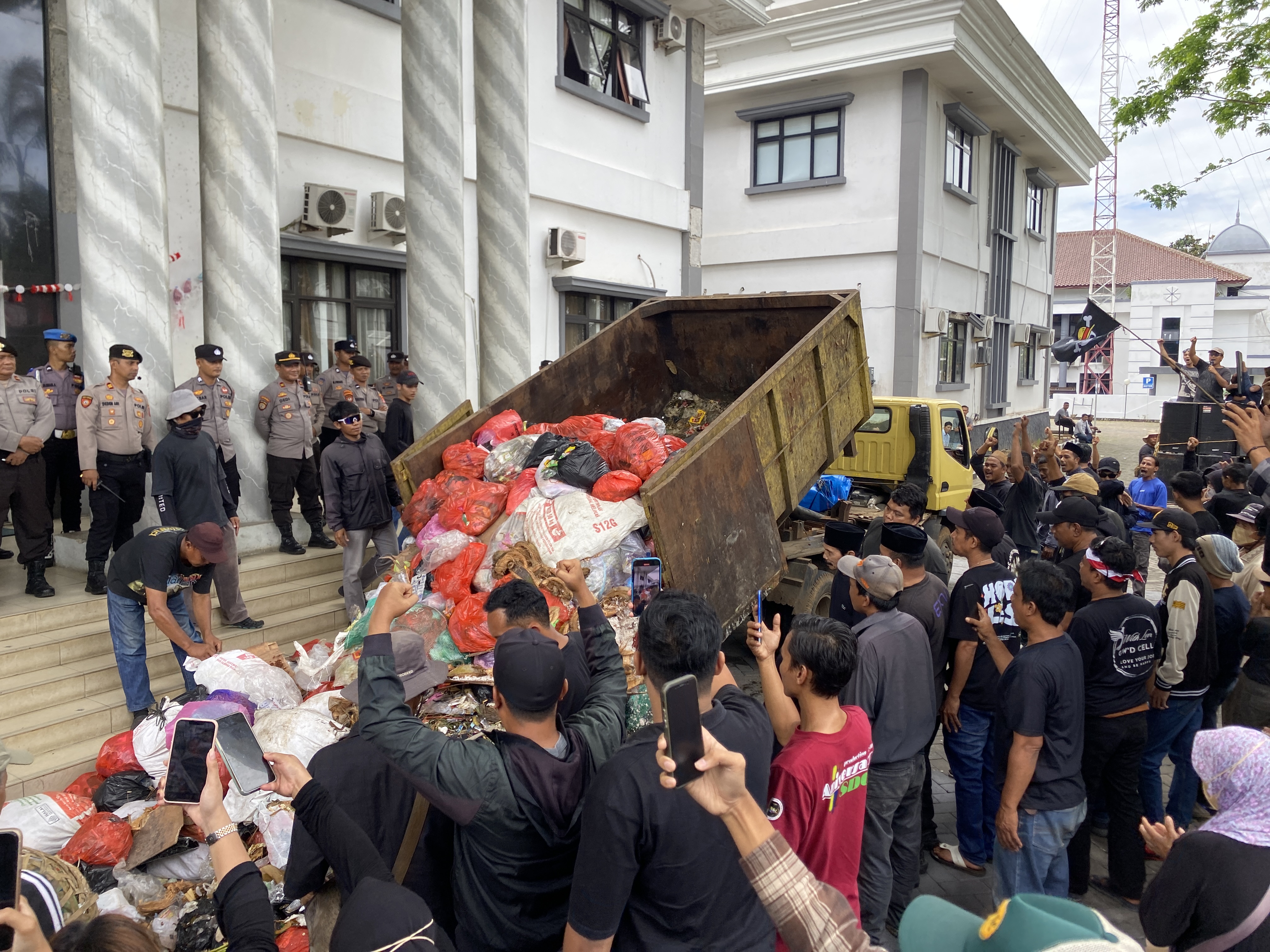 Warga sedang menumpahkan sampah dari truk saat melakukan unjuk rasa penolakan kerja sama dengan Tangsel, di halaman Kantor Bupati Pandeglang, Rabu (20/8)