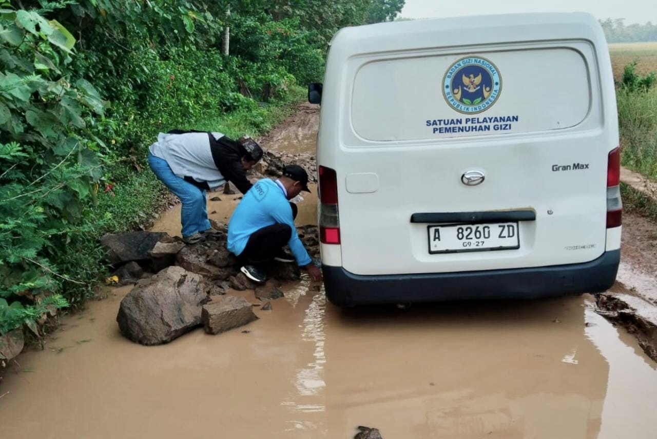 Jalan Rusak Di Pandeglang Hambat Distribusi Program MBG Pihak Tim Distribusi MBG Yayasan Cahaya Anagata Nusantara SPPG Sindanglaya 2, sedang berupaya berbagai cara agar kendaraan yang digunakannya bisa melintas di jalan rusak, dan sampai ke sekolah tepat waktu.