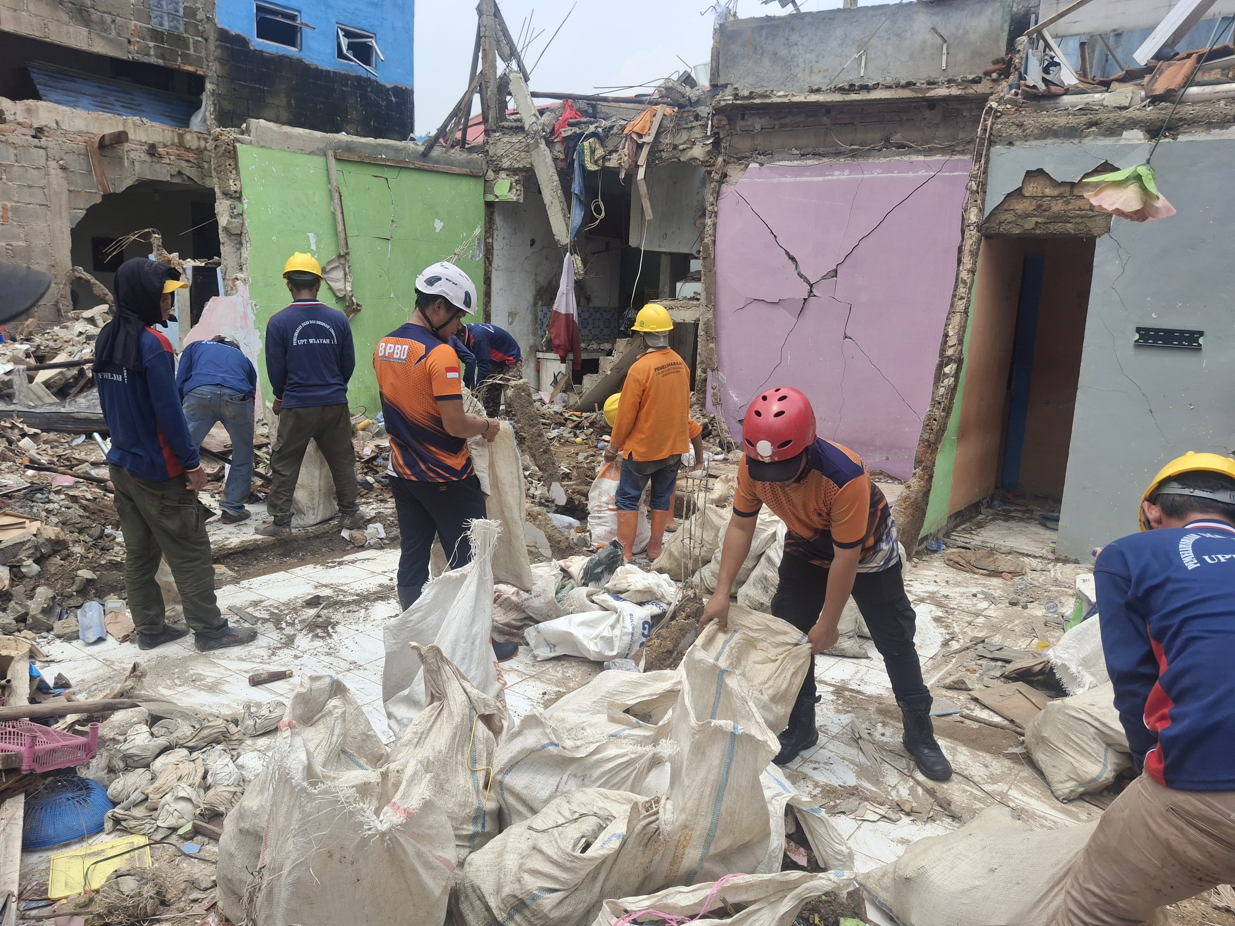 Petugas gabungan bersama warga gotong royong membersihkan puing sisa ledakan di Pamulang, Senin (15/9)