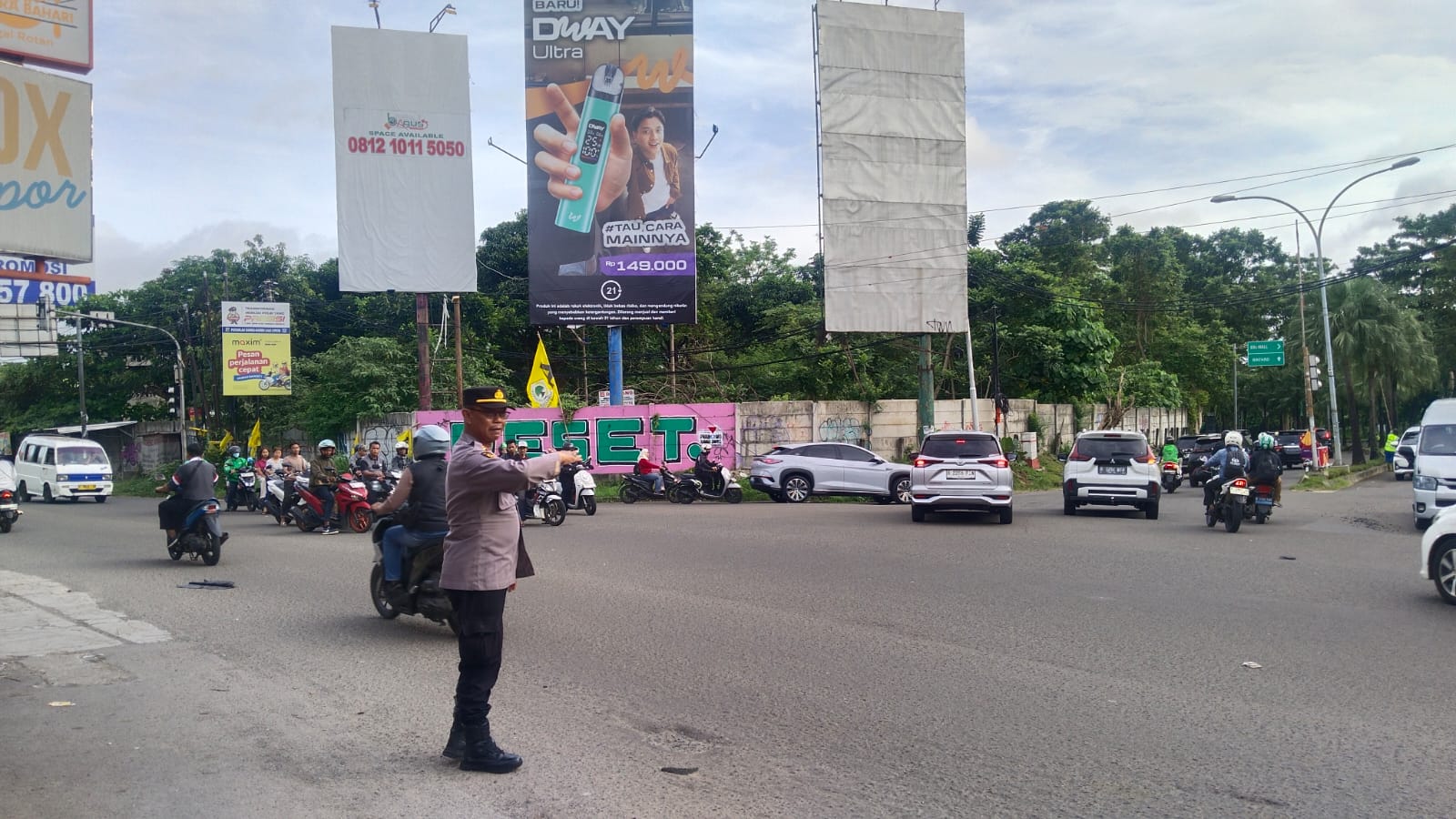 Petugas polisi mengatur lalu lintas guna melancarkan arus lalu lintas di pagi hari.