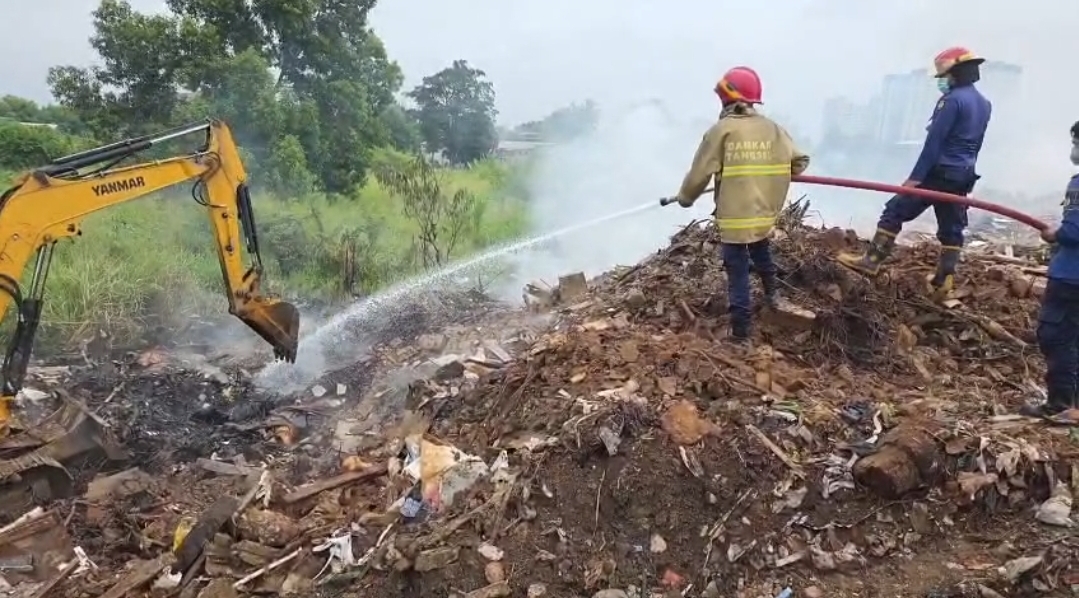 Petugas Damkar Tangsel memadamkan tumpukan sampah terbakar di Jalan Maruga Raya, Ciputat, yang sempat kembali menyala dari bawah tanah. (Ist)