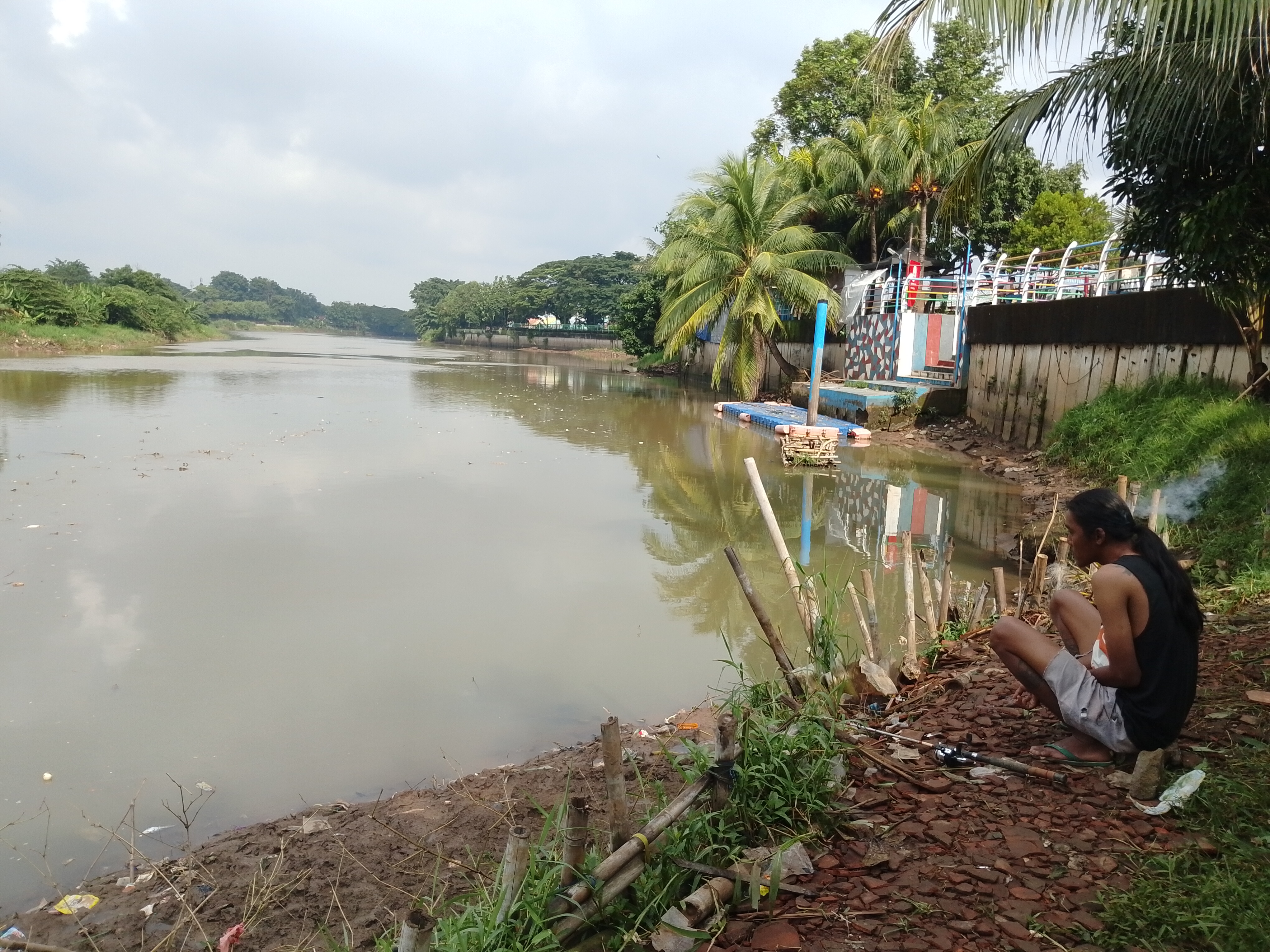 Seorang warga Kota Tangerang terlihat sedang memancing di aliran Sunga Cisadane. Kini, masyarakat diimbau untuk sementara untuk tidak memanfaatkan air dari Sungai Cisadane karena diduga tercemar.