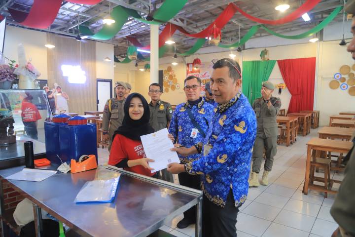 Petugas memberikan Surat Edaran Jam Operasional selama Bulan Suci Ramadan 1447 Hijriah di wilayah Kota Tangerang, Rabu (18/2).