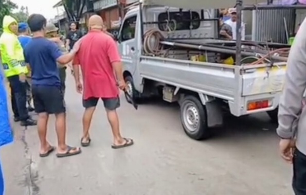 Pria berkaos merah terlihat membawa golok. Foto : Ist