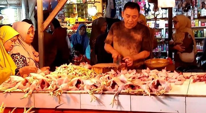 MELAYANI. Pedagang daging ayam potong sedang menjajakan dagangannya sambil melayani pembeli, di Pasar Badak Pandeglang, Senin (2/3).