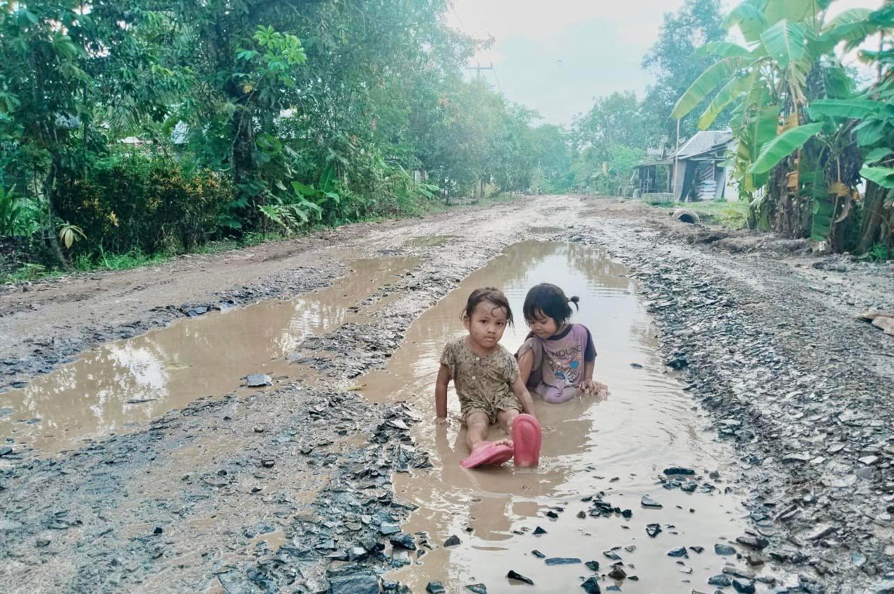 Dua orang bocah atau anak-anak warga Desa Kubangkampil, Kecamatan Sukaresmi, Kabupaten Pandeglang, terlihat asik bermain becek-becekan di Jalan penghubung Kecamatan Patia-Sukaresmi yang kondisinya rusak parah serta digenangi air pasca hujan deras, beberapa waktu lalu. (DOK. TANGSEL POS)