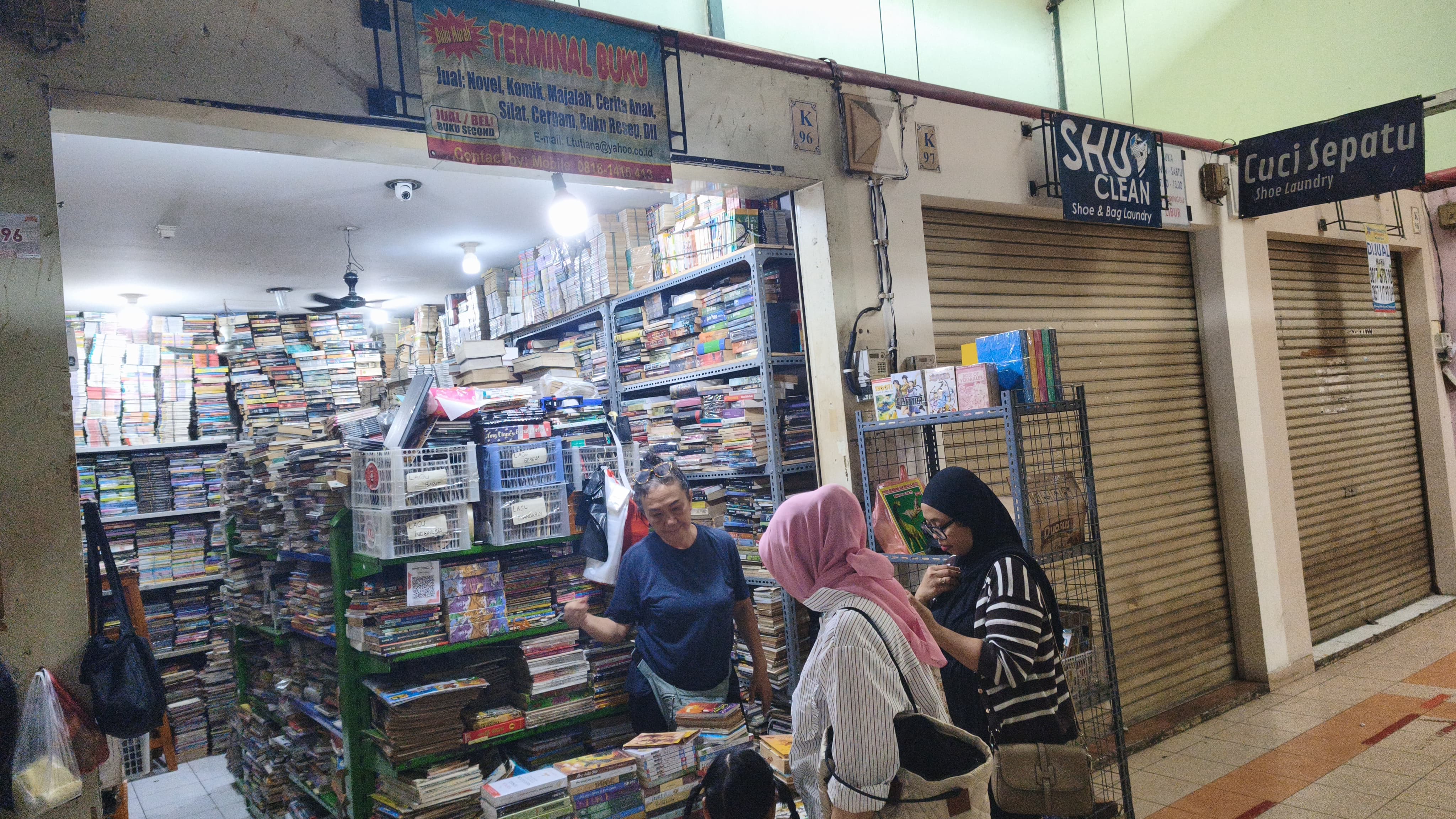 Ibu Leni, pemilik Terminal Buku, tengah melayani pelanggan yang mencari koleksi bacaan. Selain berjualan langsung di toko, Terminal Buku juga memasarkan buku-bukunya melalui berbagai platform marketplace untuk menjangkau lebih banyak pembaca. Foto : Ist