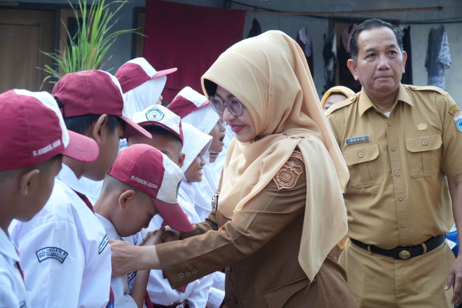 Bupati Pandeglang, Raden Dewi Setiani menyalami murid sekolah dasar pada hari pertama masuk sekolah di SDN Pandeglang 8, Senin (13/7/2026).(Istimewa)