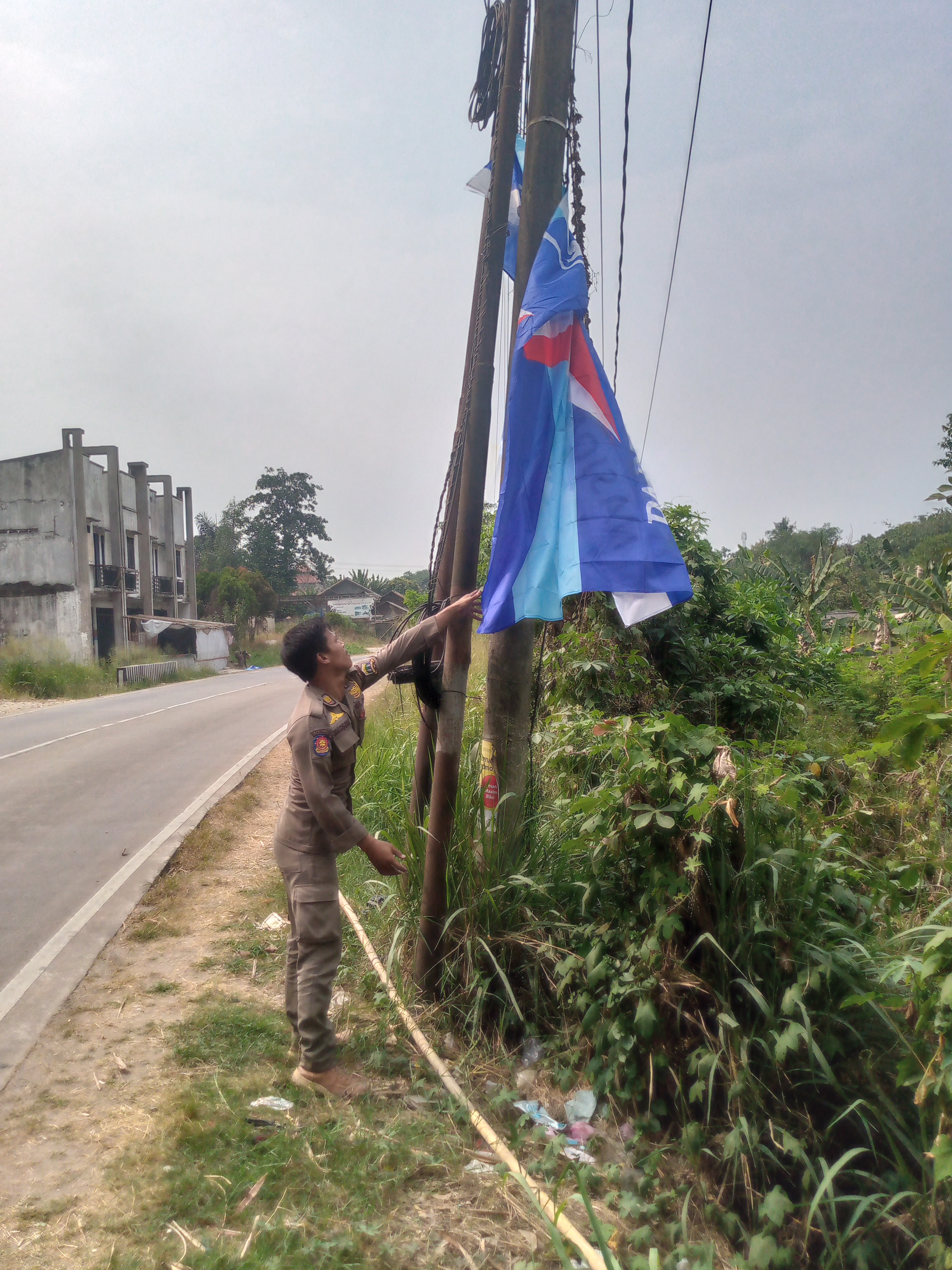 Anggota Satpol PP Kota Serang menertibkan bendera Partai Demokrat di Jalan Syekh Moh. Asnawi al-Bantani, Kota Serang, Jumat (31/7/2026).(Ari Supriadi-tangselpos.id)