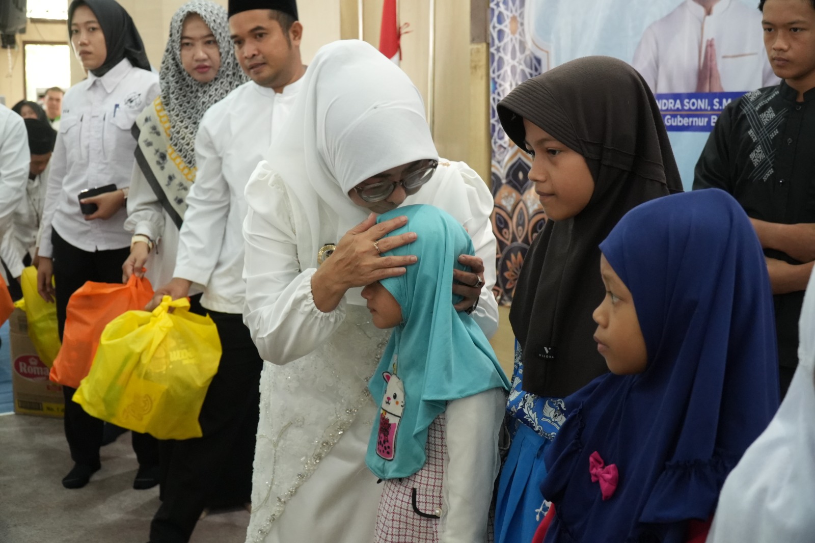 MENCIUM ANAK YATIM. Bupati Pandeglang Raden Dewi Setiani, telah menyantuni dan mencium kepala salah seorang anak yatim, disela-sela peringatan Maulid Nabi Muhammad SAW 1448 Hijriah, di Aula Pendopo Negara Bupati Pandeglang, Kamis (17/9). (DOK. PROKOPIM SETDA PANDEGLANG)