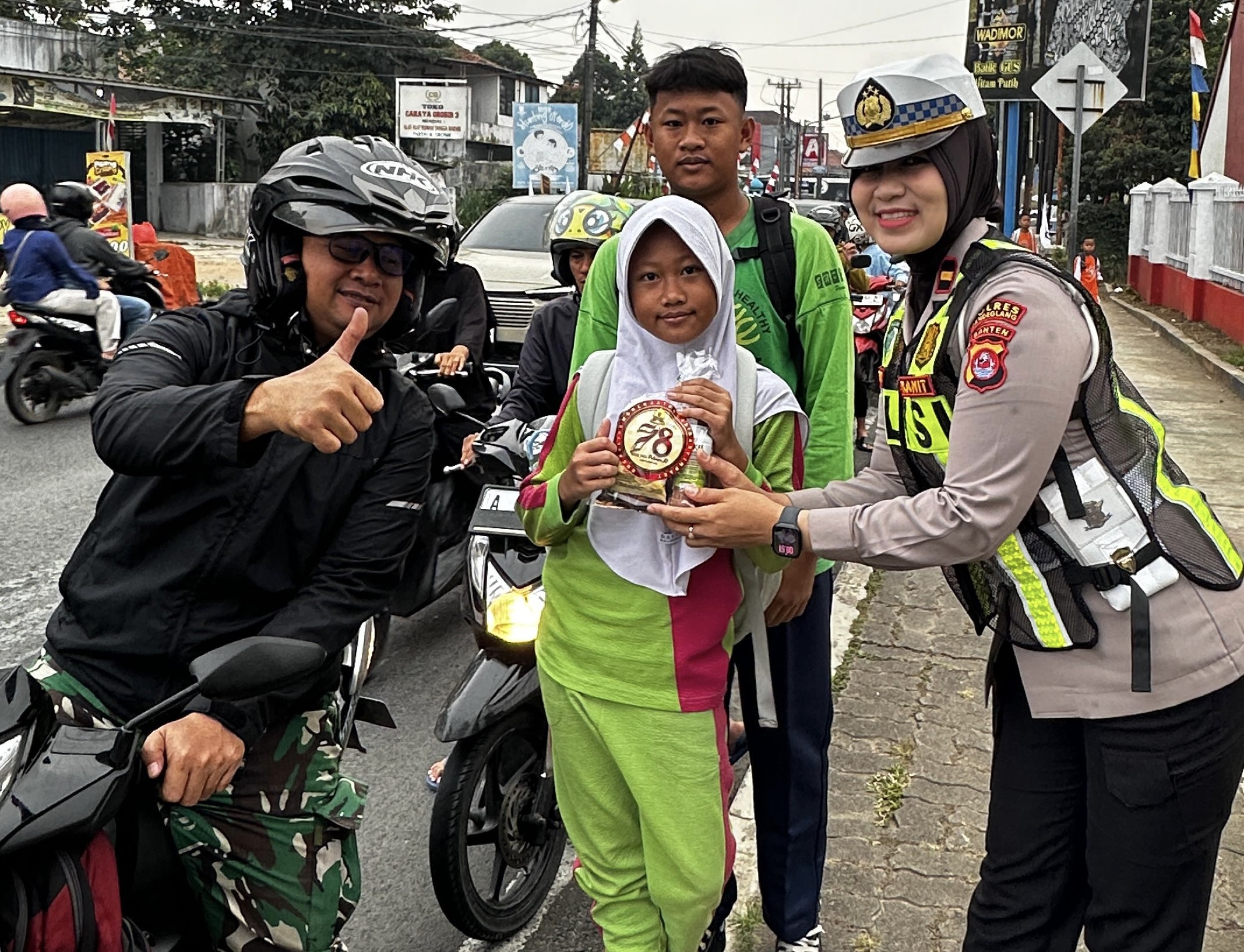 BERI HAMPERS. Anggota Polisi Wanita Polres Pandeglang, sedang memberikan hampers kepada anak sekolah dan para pengguna jalan lainnya, di wilayah Alun-alun Kabupaten Pandeglang, Selasa (1/9). (ISTIMEWA)