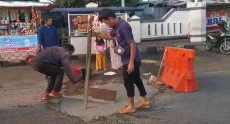 Sejumlah pedagang kali lima (PKL) dan tukang ojek yang biasa mangkal di Jalan Bhayangkara atau di depan Kantor Bupati Pandeglang, memperbaiki jalan tersebut secara swadaya dan swadana, Rabu (13/7/2022).(Istimewa)