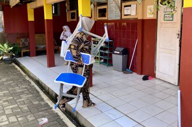 Wali murid Arta Grace Monica (35) sedang menggendong meja dan menjinjing kursi, untuk disimpan ke dalam kelas IV SDN 2 Pasir Tangkil, beberapa waktu lalu.